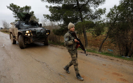 A member of Turkey-backed Free Syrian Army police forces secures the road as they escort a convoy near Azaz, Syria January 26, 2018. REUTERS/Umit Bektas