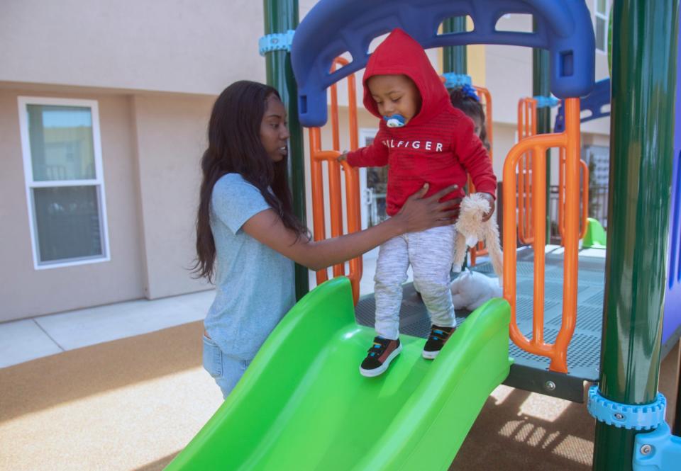 Resident Deshawna Harris and her 2-year-old son Andre Armstrong play in the playground during the grand opening ceremony for Liberty Square.