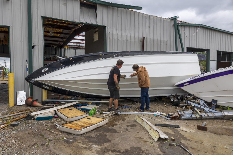 Hank Plauche, right, looks at the bottom of his overturned boat on Thursday, April 11, 2024, at Scotty's Performance Boat & Marine in Slidell, La,, the day after a tornado hit the area. (Chris Granger/The Times-Picayune/The New Orleans Advocate via AP)t