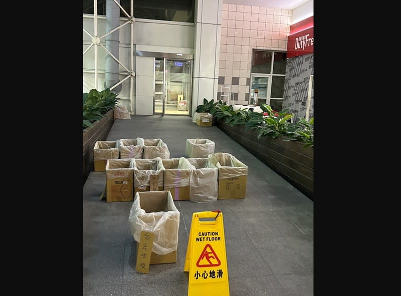 高雄28日大雨造成高雄國際機場多處漏水，出境大廳擺水桶、鋪紙板，戶外通道也放紙箱接漏水。（中央社／民眾提供）