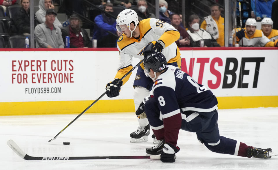 Nashville Predators center Ryan Johansen, back, passes the puck as Colorado Avalanche defenseman Cale Makar covers in the second period of an NHL hockey game Saturday, Nov. 27, 2021, in Denver. (AP Photo/David Zalubowski)