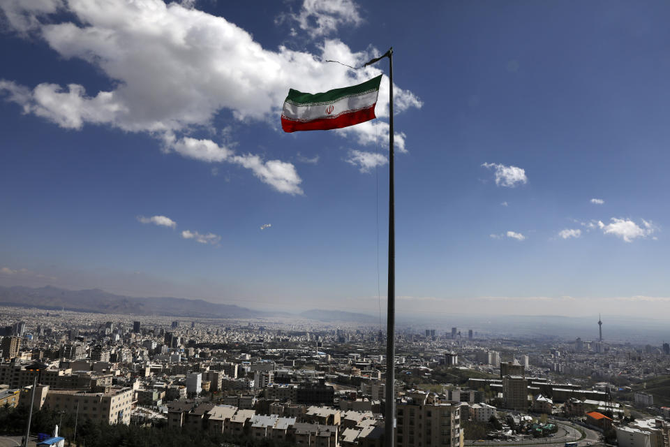 Iran's national flag waves in northern Tehran, Iran, Tuesday, March 31, 2020. In recent days, Iran which is battling the worst new coronavirus outbreak in the region, has ordered the closure of nonessential businesses and banned intercity travels aimed at preventing the virus' spread. (AP Photo/Vahid Salemi)