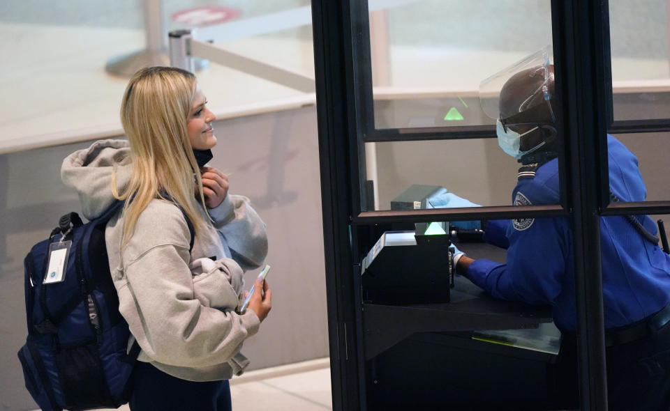 A traveler smiles as they pull down their mask for a TSA agent to confirm their identity at the security checkpoint at Love Field airport Friday, May 28, 2021, in Dallas. (AP Photo/LM Otero)