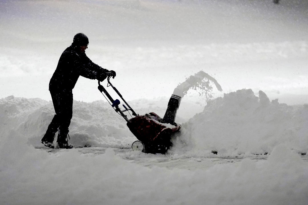 A person clears snow from a driveway in Urbandale, Iowa