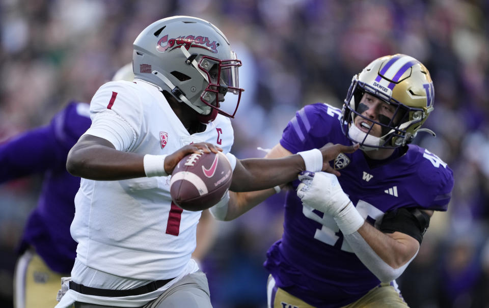 Washington State quarterback Cameron Ward blocks Washington linebacker Carson Bruener as he runs with the ball during the first half of an NCAA college football game, Saturday, Nov. 25, 2023, in Seattle. (AP Photo/Lindsey Wasson)