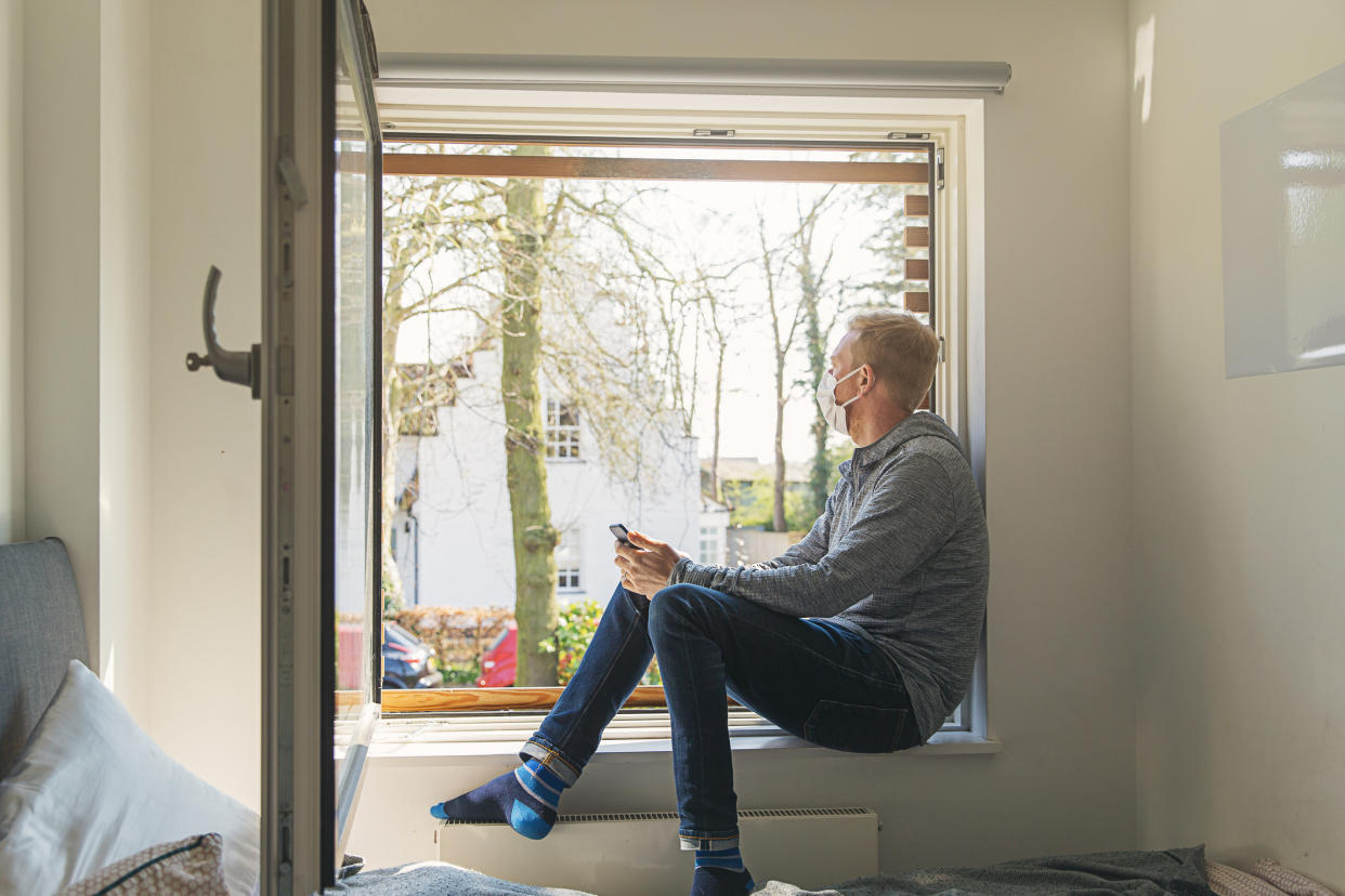 Man with mask looking out of window