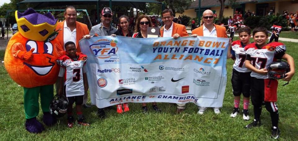 La mascota de Orange Bowl, OBIE, y los miembros del Orange Bowl Committee, Sergio Abreu, George Pino y Albert de Cárdenas, junto con los representantes de Kendall Hammocks Warriors, Mike Pintado, Meylin Castro y Shirley Pintado, y sus jugadores en 2016.