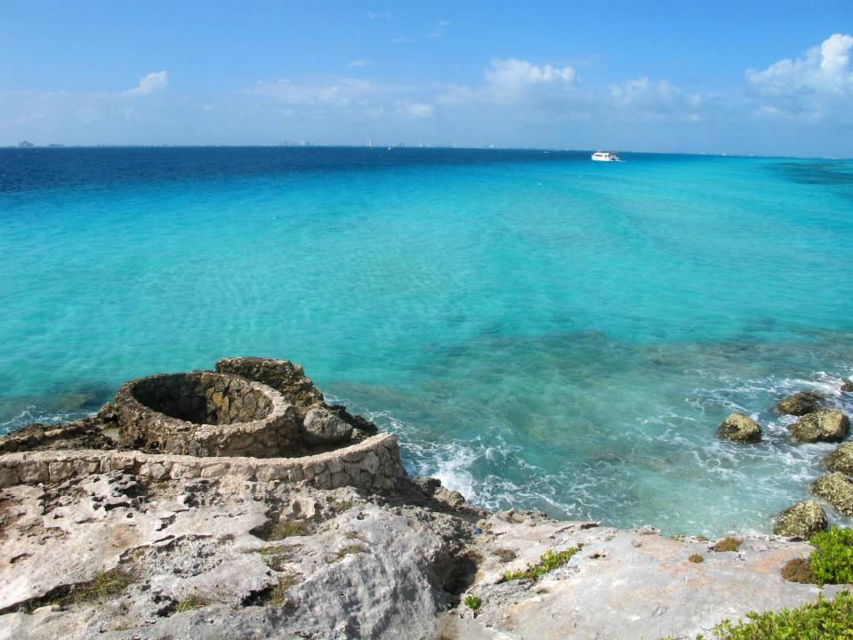 This November 2012 photo shows the view of Cancun across the bay from the southernmost point of Isla Mujeres, also known as Punta Sur, where visitors can walk on developed trails amid dramatic cliffs to the very tip of the ocean. Isla Mujeres, or Island of Women, is a tiny 5-mile-long, half-mile wide island just a half-hour's ferry ride across from Cancun, with far fewer visitors and a much calmer, romantic atmosphere. (AP Photo/Amanda Lee Myers)