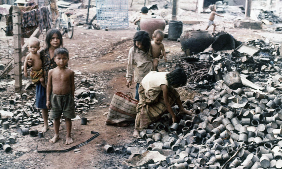 FILE - In this February 1974, file photo, Cambodian children scavenge amidst the ruins left by the fierce insurgent Khmer Rouge rocket and artillery attack on a shanty town on the edge of Phnom Penh, Cambodia. The last surviving leaders of the communist Khmer Rouge regime that brutally ruled Cambodia in the 1970s were convicted of genocide, crimes against humanity and war crimes Friday, Nov. 16, 2018, by an international tribunal. (AP Photo/Carl D. Robinson, File)