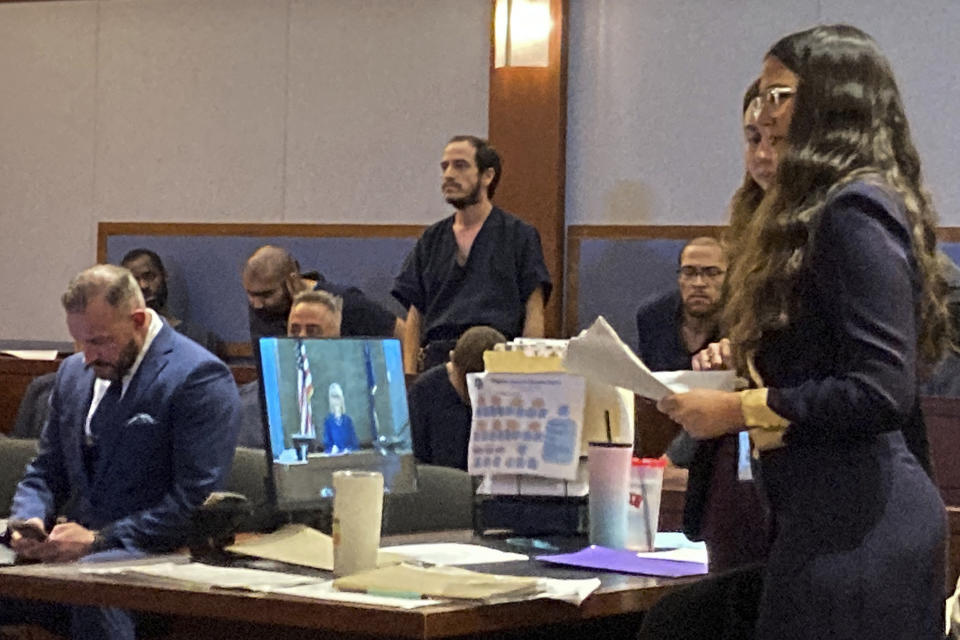 CORRECTS YEAR OF SHOOTING TO 2019, NOT 2021 - Michael Sanchez, rear center, stands in custody in Las Vegas Justice Court on Wednesday, Feb. 1, 2023, while Erica Webb, right, a Clark County Public Defender's office law clerk, speaks during Sanchez's initial appearance on a felony terrorism threat charge. Sanchez, 37, was arrested in Las Vegas on Sunday, Jan. 29, 2023. He is accused of telephoning threats to "shoot up" a Southern Nevada synagogue and allegedly referred to a San Diego-area synagogue shooting that killed one person and injured three in 2019. (AP Photo/Ken Ritter)