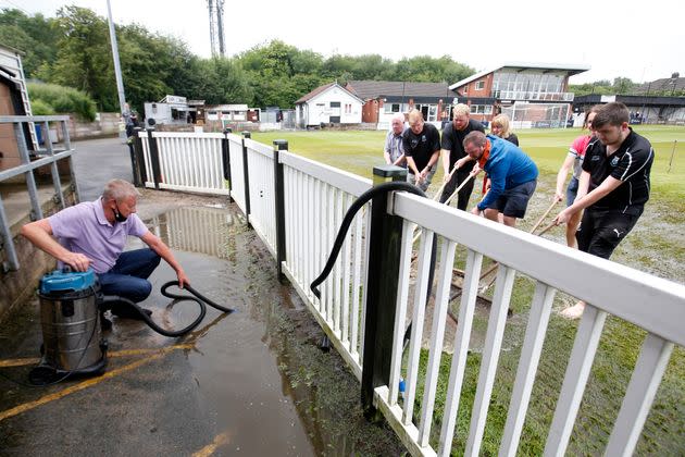 Staff work on a waterlogged pitch before a cricket game at Sir Tom Finney Stadium in Blackburn on July 10 (Photo: Ed Sykes - CameraSport via Getty Images)