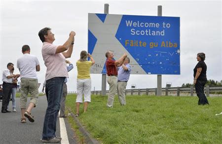 Swiss tourists take photographs next to a road that marks the England - Scotland border, at a lay-by on the A1 road near Berwick August 20, 2013. REUTERS/Toby Melville