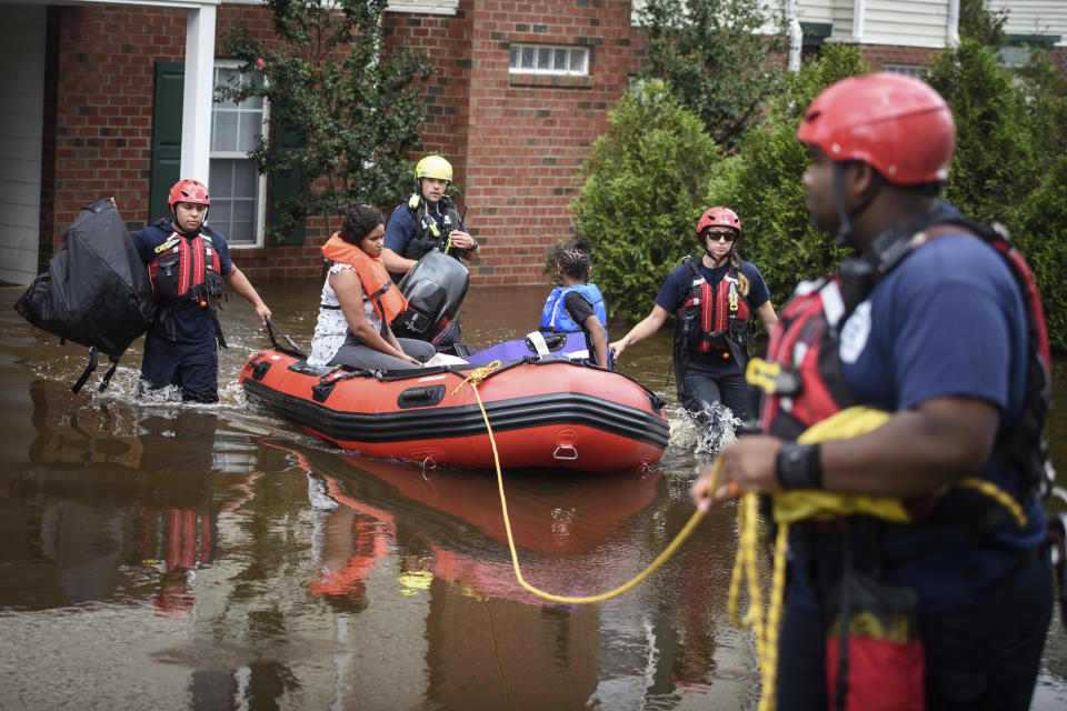 Emergency personnel take a family to safety after Little River overflowed its banks and flooded part of the apartment complex on Monday, Sept. 17, 2018, in Spring Lake, N.C. North Carolina Gov. Roy Cooper warned that the flooding set off by rain from Florence is far from over and will get worse in places. (Andrew Craft/The Fayetteville Observer via AP)