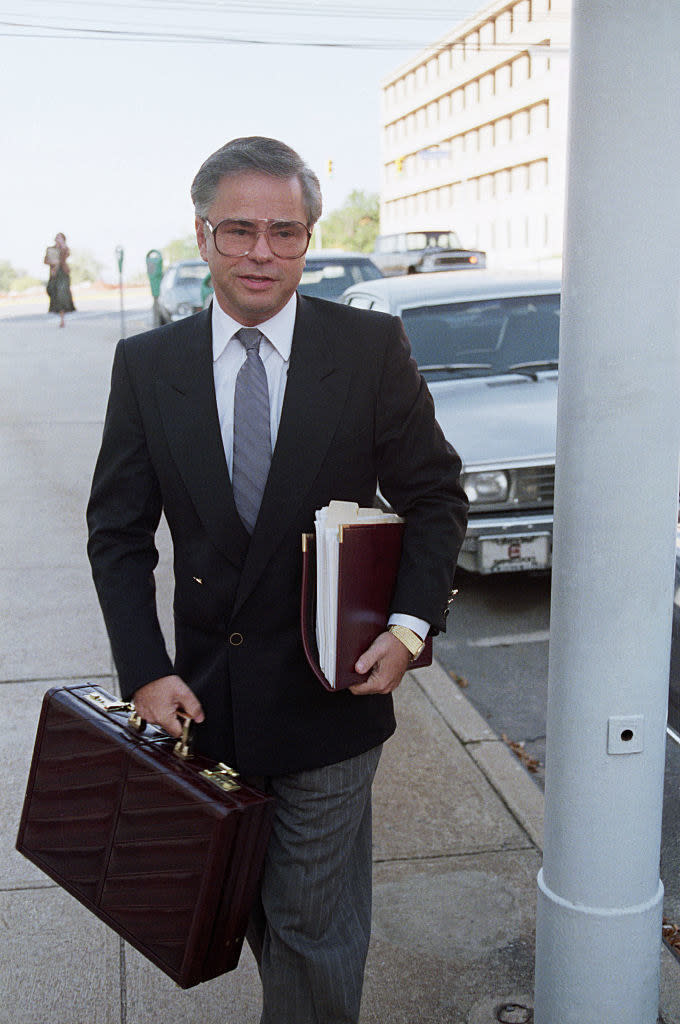 Jim in a suit with a briefcase and files walking down the street