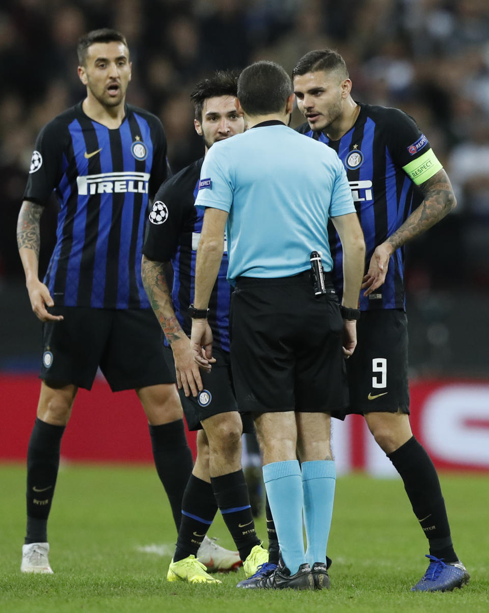 From left, Inter Milan's Matias Vecino and his teammates Matteo Politano and Mauro Icardi argue with referee Cuneyt Cakir during the Champions League group B soccer match between Tottenham Hotspur and Inter Milan at the Wembley stadium in London, Wednesday, Nov. 28, 2018. (AP Photo/Alastair Grant)