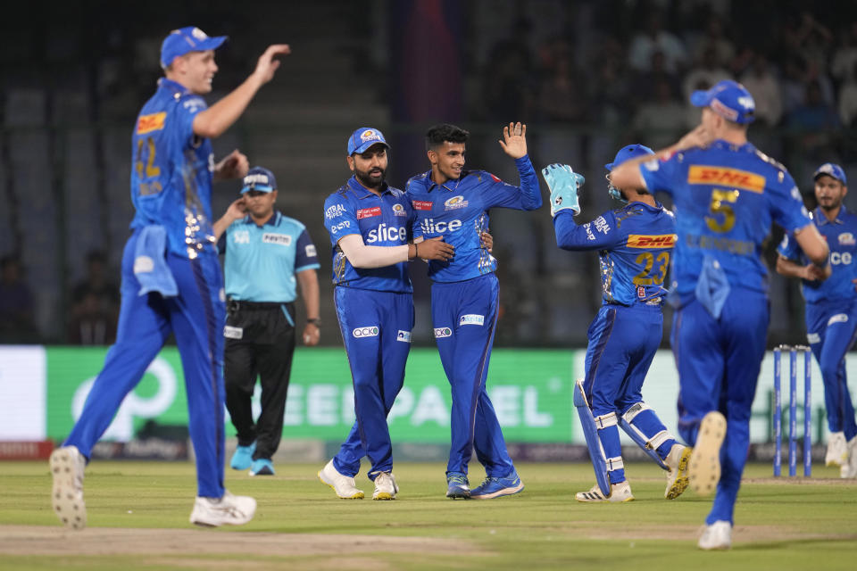 Mumbai Indians's captain Rohit Sharma congratulates teammate Hrithik Shokeen as others celebrate the wicket of Delhi Capitals' Prithvi Shaw during the Indian Premier League (IPL) match between Delhi Capitals and Mumbai Indians in New Delhi, India, Tuesday, April 11, 2023. (AP Photo/Manish Swarup)