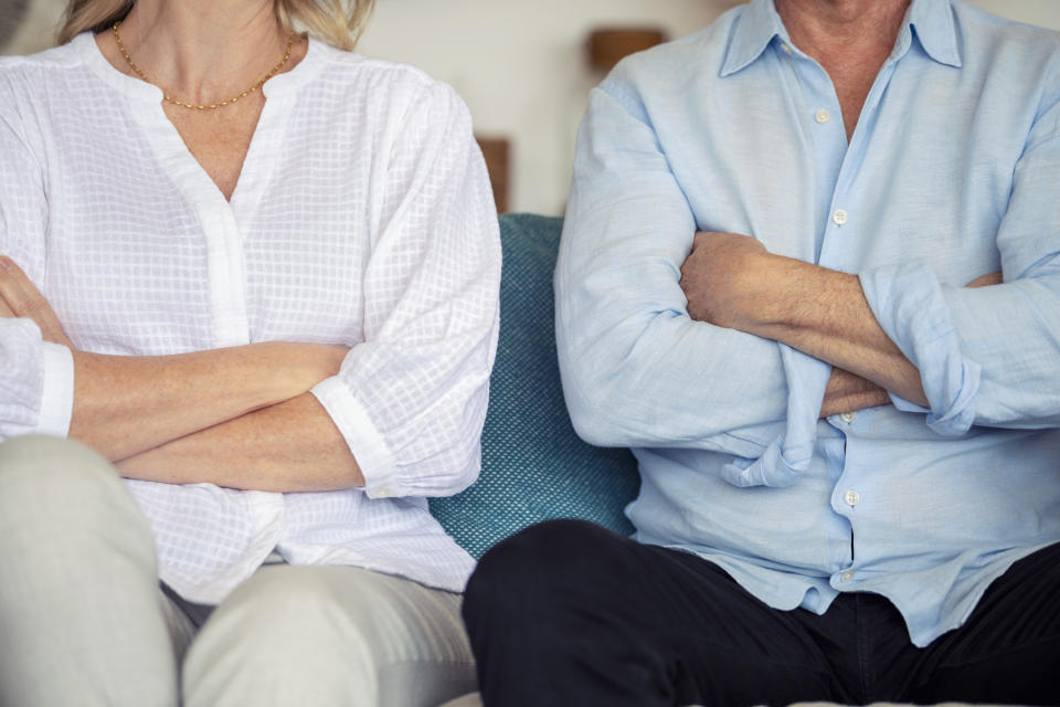 Two adults seated side by side, both with arms crossed, signifying a potential disagreement or standoff