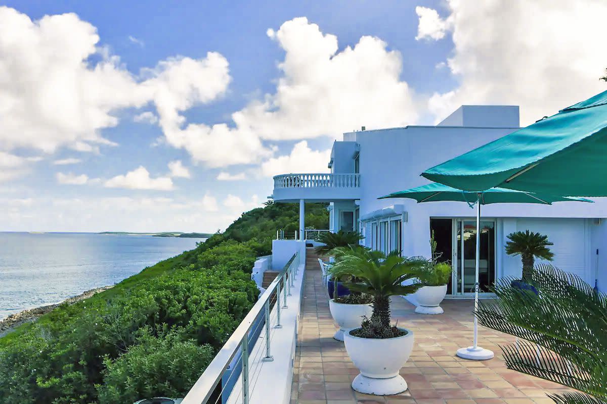 An exterior shot of the Villa Stella Maris, surrounded by palm trees with a blue ocean in the background