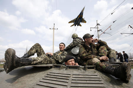 A fighter jet flies above as Ukrainian soldiers sit on an armoured personnel carrier in Kramatorsk, in eastern Ukraine April 16, 2014. REUTERS/Marko Djurica