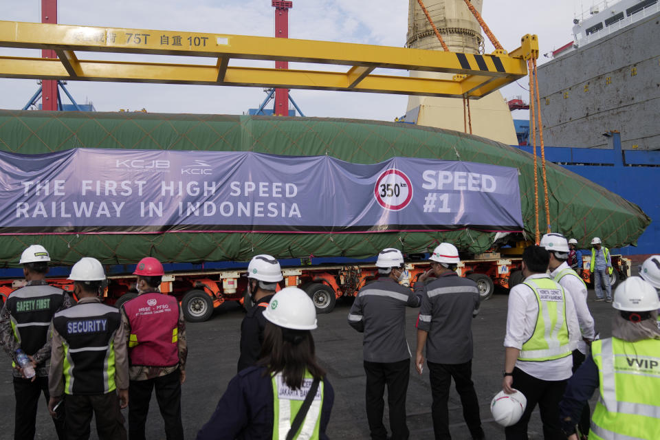 Workers and officials watch as a part of Chinese-made high-speed passenger train is placed onto a truck at Tanjung Priok Port in Jakarta, Indonesia, Friday, Sept. 2, 2022. The first high-speed electric train which is prepared for the Jakarta-Bandung High-Speed Railway arrived in the capital city on Friday. (AP Photo/Dita Alangkara)