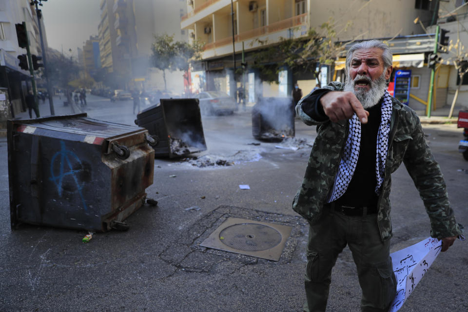 A protester shouts slogans in front of burning garbage containers used to block a main road during a protest against the increase in prices of consumer goods and the crash of the local currency, in Beirut, Lebanon, Tuesday, March 16, 2021. Scattered protests broke out on Tuesday in different parts of the country after the Lebanese pound hit a new record low against the dollar on the black market. (AP Photo/Hussein Malla)