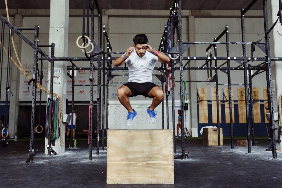 young athlete exercising box jumps at gym
