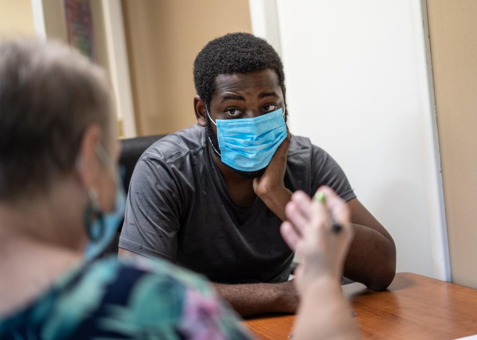 Macomb County Rotating Emergency Shelter Team (MCREST) case manager Jane Mahoney asks questions to Taijh Robinson of Warren while seeing how their program can help him out after becoming homeless following a fire to his mother's home on July 26, 2021 at the MCREST building in Roseville.