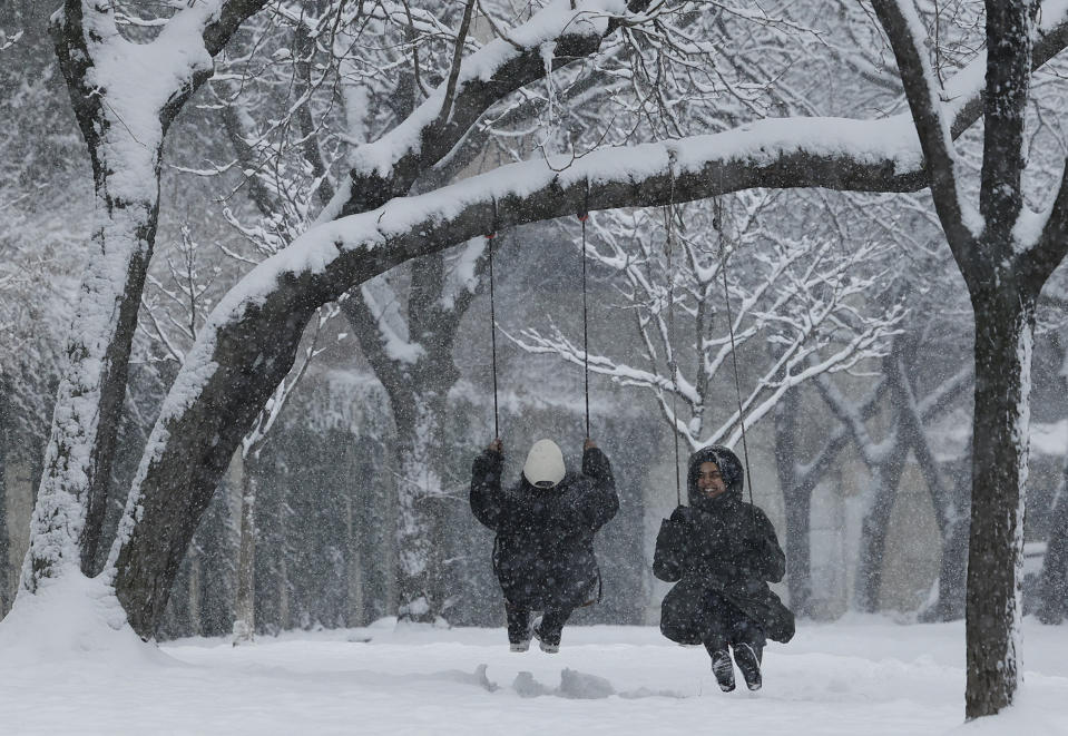 Sadia Afreen, right, and Shirin Akhter enjoy the snow fall while riding on swings in the Wood Street Park in the Old City neighborhood of Philadelphia, Friday, Jan. 19, 2024. (Yong Kim/The Philadelphia Inquirer via AP)