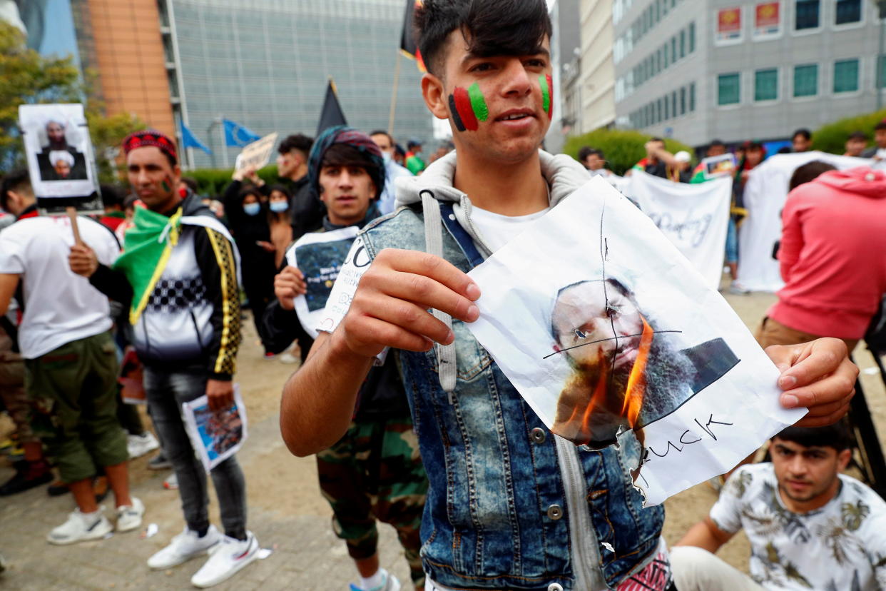 A demonstrator burns a picture of Taliban leader Mullah Haibatullah Akhundzada during an anti-Taliban protest, in Brussels, Belgium, August 18, 2021. REUTERS/Johanna Geron