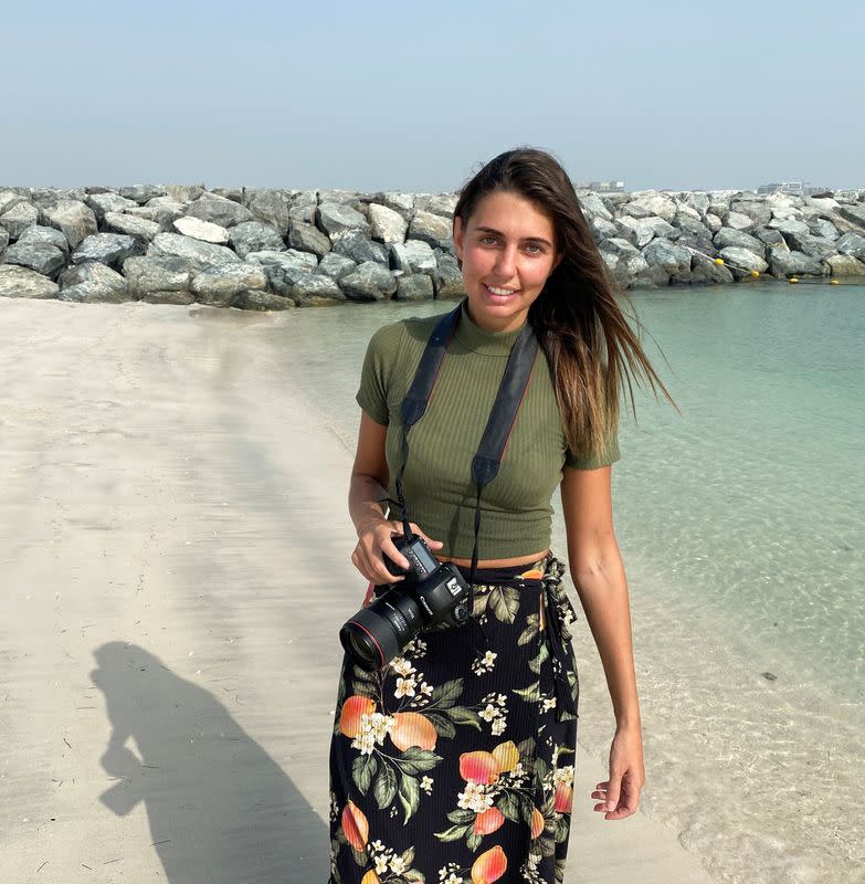 Paula Hainey, a photographer poses for a photo at the beach, as she gives free photo sessions for families who lost their jobs and will be leaving Dubai due the coronavirus pandemic, in Dubai