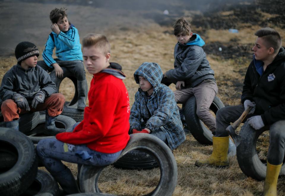 In this photo taken on Sunday, March 10, 2019, a children sit on tires during a ritual marking the upcoming Clean Monday, the beginning of the Great Lent, 40 days ahead of Orthodox Easter, on the hills surrounding the village of Poplaca, in central Romania's Transylvania region. Romanian villagers burn piles of used tires then spin them in the Transylvanian hills in a ritual they believe will ward off evil spirits as they begin a period of 40 days of abstention, when Orthodox Christians cut out meat, fish, eggs, and dairy. (AP Photo/Vadim Ghirda)