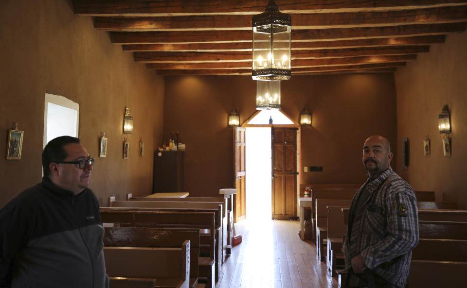 Fidel Trujillo, left, and Leo Paul Pacheco, stand inside the 1880s Santo Niño de Atocha chapel in Monte Aplanado, New Mexico, on Saturday, April 15, 2023. Pacheco restored the adobe walls of the church, and hopes that his children will value doing the same in the future, maintaining cherished Catholic traditions in these remote mountain villages. (AP Photo/Giovanna Dell'Orto)