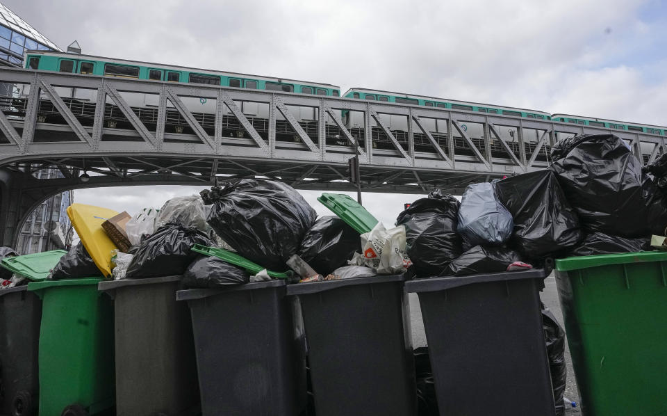 Not collected garbage cans are pictured as subway train crosses the Bir-Hakeim bridge over Seine in Paris, Sunday, March 12, 2023. A contentious bill that would raise the retirement age in France from 62 to 64 got a push forward with the Senate's adoption of the measure amid strikes, protests and uncollected garbage piling higher by the day. (AP Photo/Michel Euler)