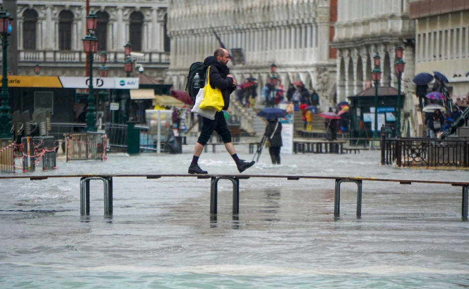 A man walks on a trestle bridge as high water floods Venice, northern Italy, Sunday, Nov. 24, 2019. The high water reached peak of 135cm (4.42ft) early Sunday. (Andrea Merola/ANSA via AP)