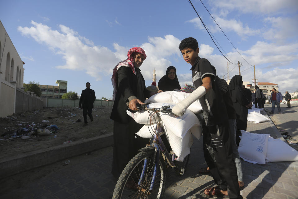 Palestinians transport flour distributed by the U.N. during the ongoing Israeli bombardment of the Gaza Strip in Rafah on Tuesday, Nov. 21, 2023. (AP Photo/Hatem Ali)