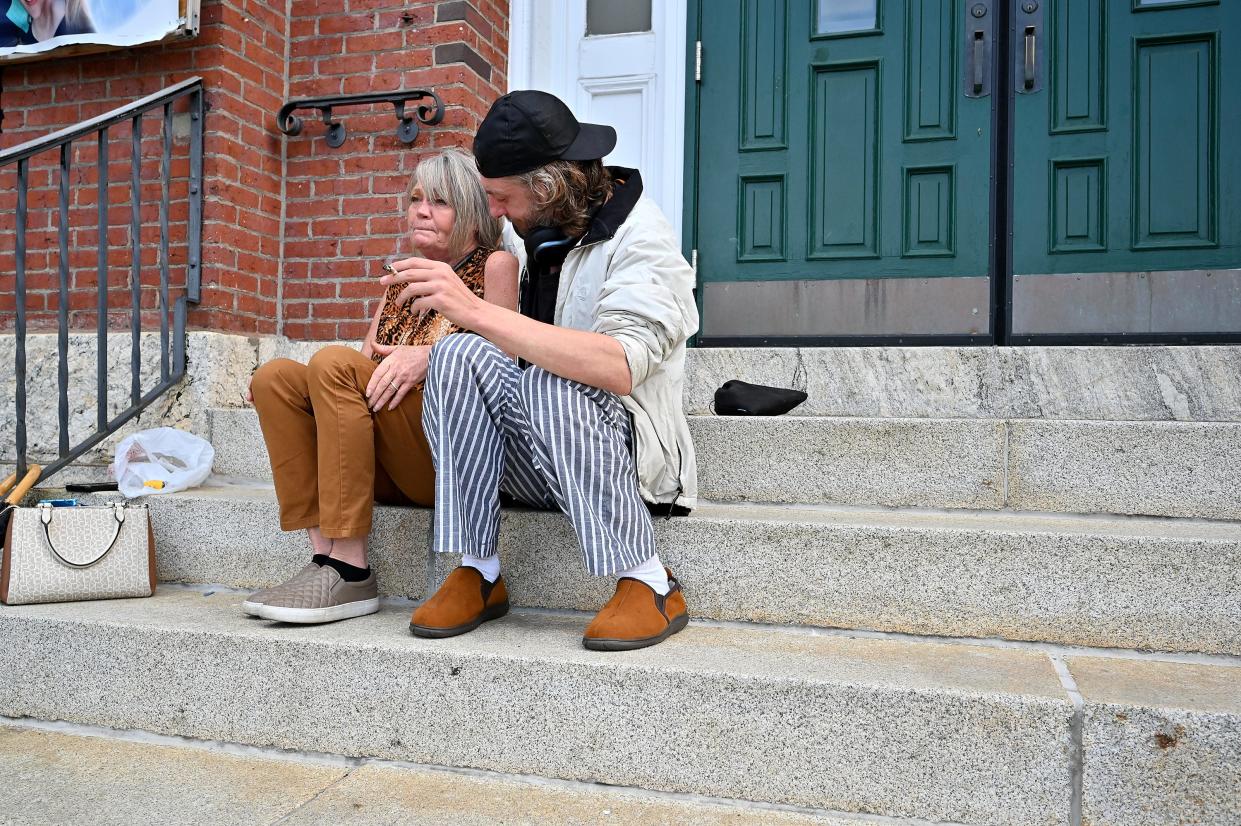 Rachel McMorris and Calon Milan, homeless at that time, sit on the front steps at St. John's Catholic Church on Temple Street last month.