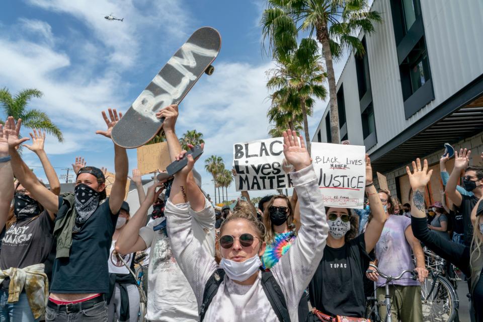 Protestors hold their hands up and march during a demonstration over the death of George Floyd in the Venice area of Los Angeles on June 2, 2020. - Anti-racism protests have put several US cities under curfew to suppress rioting, following the death of George Floyd in police custody. (Photo by Kyle Grillot / AFP) (Photo by KYLE GRILLOT/AFP via Getty Images)