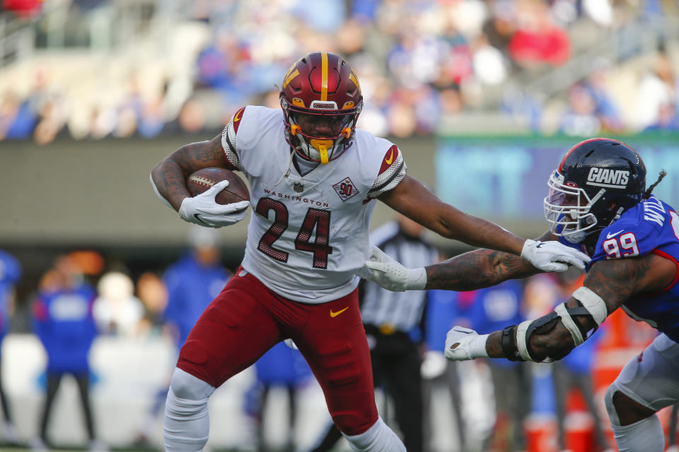 Washington Commanders' Antonio Gibson, left, runs the ball during the first half of an NFL football game against the New York Giants, Sunday, Dec. 4, 2022, in East Rutherford, N.J. (AP Photo/John Munson)