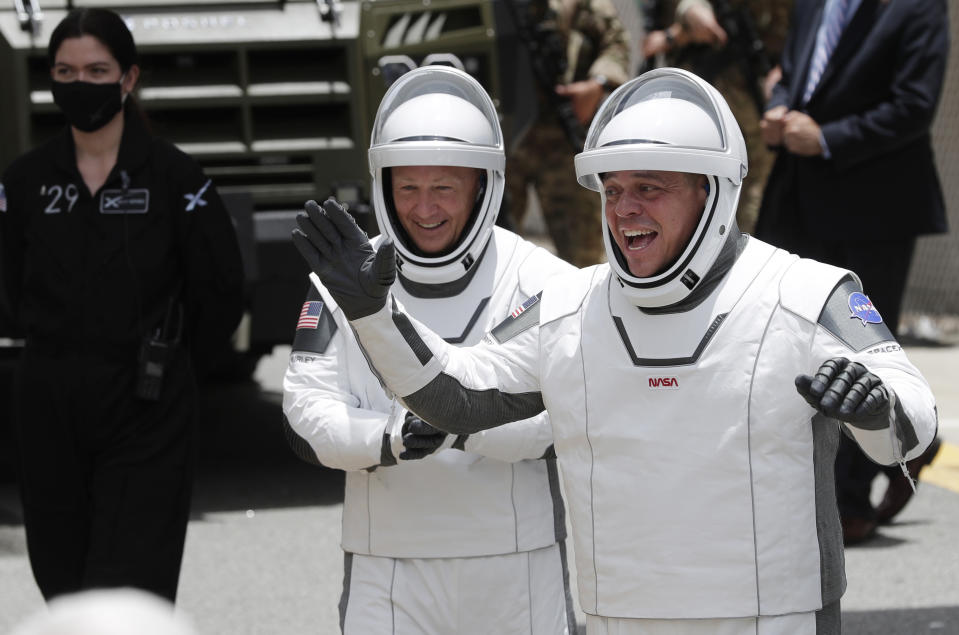 NASA astronauts Douglas Hurley, left, and Robert Behnken wave as they walk out of the Neil A. Armstrong Operations and Checkout Building on their way to Pad 39-A, at the Kennedy Space Center in Cape Canaveral, Fla., Wednesday, May 27, 2020. The two astronauts will fly on a SpaceX test flight to the International Space Station. For the first time in nearly a decade, astronauts will blast into orbit aboard an American rocket from American soil, a first for a private company. (AP Photo/John Raoux)