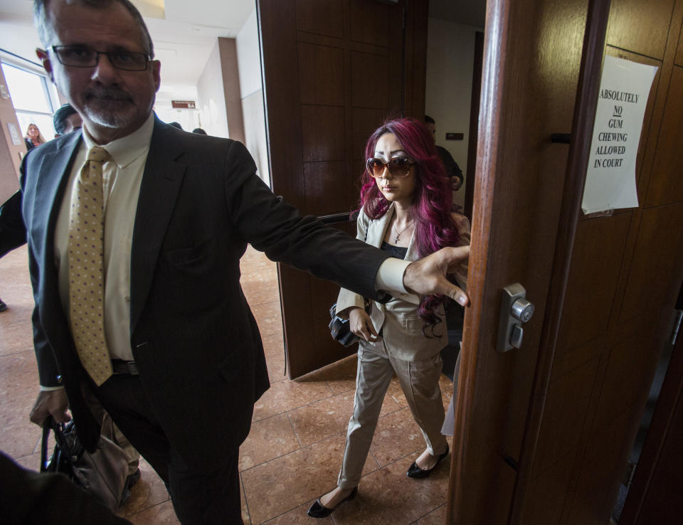 Gloria Lee, 35, who is facing charges of arson following a Jan. 27 fire at her Prince and Princess Pet Boutique in Las Vegas, leaves Clark County Justice Court with her attorney Ozzie Fumo Wednesday, Feb. 5, 2014, in Las Vegas. Lee surrendered her passport at the demand of Justice of the Peace Joe Sciscento. A total of 27 puppies were rescued and taken to the shelter after the attempted arson. (AP Photo/Las Vegas Review-Journal, Jeff Scheid) LOCAL TV OUT; LOCAL INTERNET OUT; LAS VEGAS SUN OUT