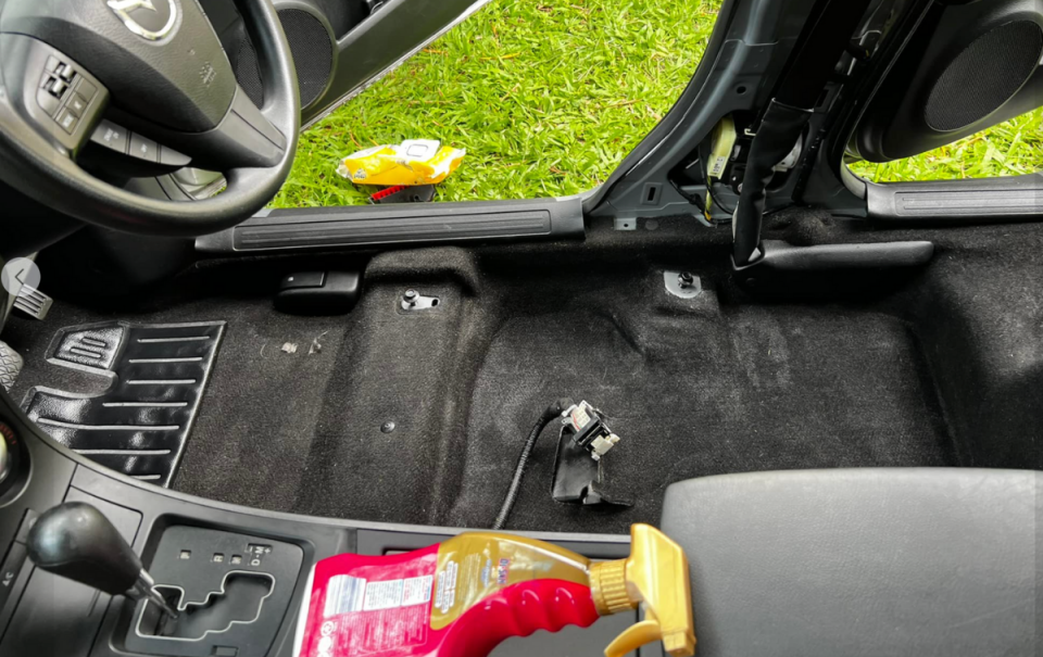 The front section of the car, with seat removed showing clean black carpet on the driver's side and Aldi Di San