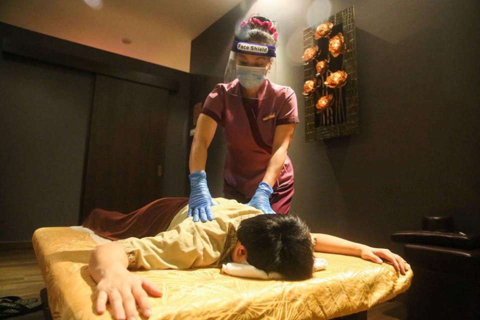 A therapist decked in protectice gear gives a demonstration of standard operating procedures that will be adhered to during a Thai massage at the Healthland Wellness Centre in Sunway Pyramid June 30, 2020. — Picture by Choo Choy May