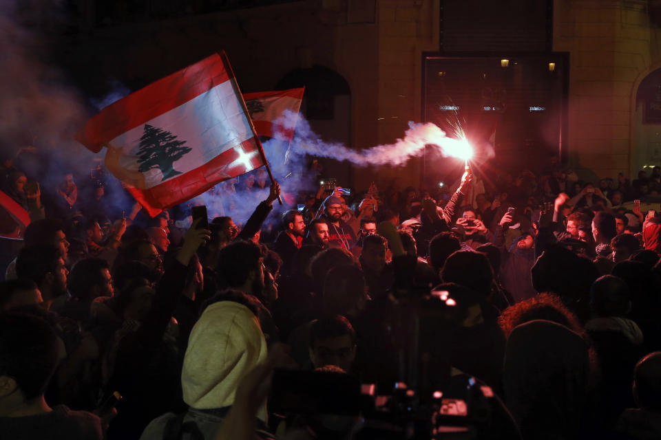 Anti-government demonstrators hold flares and Lebanese flags, during a protest on a road leading to the parliament building in Beirut, Lebanon, Thursday, Jan. 16, 2020. Lebanese protesters Thursday decried security forces' use of violence during rallies over the past two days, including attacks on journalists and the detention of over 100 people. (AP Photo/Bilal Hussein)