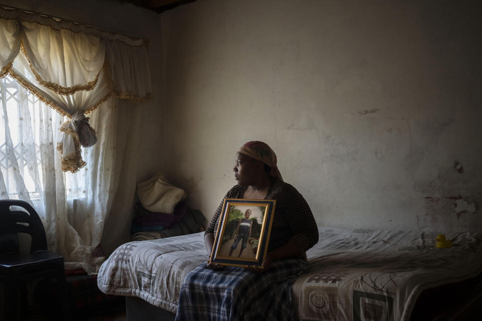 Rebecca Mohapi poses with a photograph in the bedroom of her son, 12-year-old Onthatile Mohapi, who mysteriously disappeared and was found dead a week later in Damonsville, South Africa, on June 8, 2020. The police report said the boy drowned, but his mother believes he was murdered. (AP Photo/Bram Janssen)