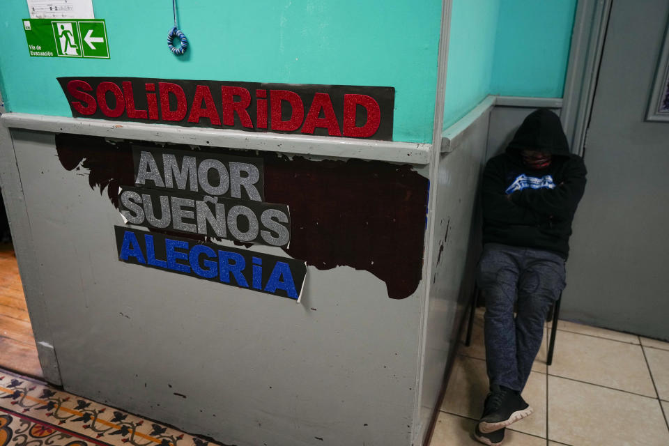 A homeless man rests at the entrance to the shelter "Hogar de Cristo," or Christ's Home in Santiago, Chile, Wednesday, May 15, 2024. The words in Spanish read "Solidarity. Love. Dreams. Joy." (AP Photo/Esteban Felix)