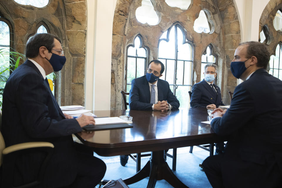 In this photo provides from Cyprus press and information office, Cypriot Foreign Minister Nicos Christodoulides, center, looks on with Cyprus President Nicos Anastasiades, left, as he talks with Britain's Secretary of State for Foreign Affairs, Dominic Raab, right, during their meeting at the Presidential Palace in capital Nicosia, Cyprus, Thursday, Feb. 4, 2021. Raab is in Cyprus for one day of talks. (Stavros Ioannides / PIO via AP)