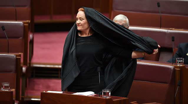 Senator Hanson takes off the burqa before announcing her motion on banning them. Photo: AAP