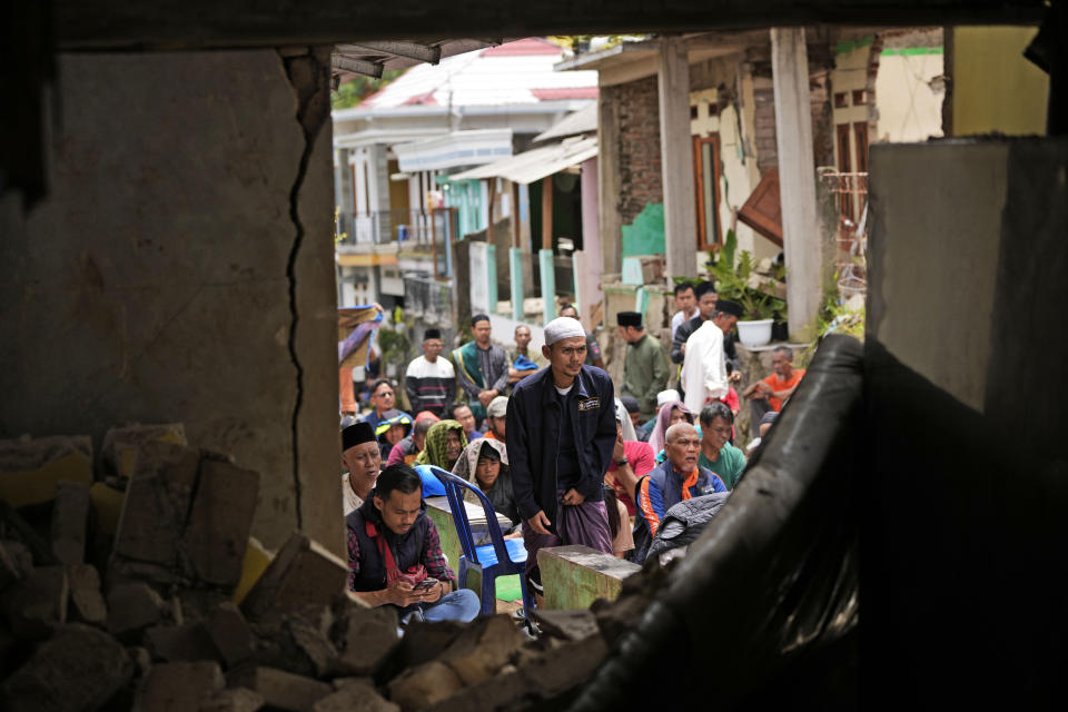 Men are seen through a building damaged in Monday's earthquake as they prepare to perform Friday prayer in Cianjur, West Java, Indonesia, Friday, Nov. 25, 2022. The quake on Monday killed hundreds of people, many of them children and injured thousands. (AP Photo/Achmad Ibrahim)