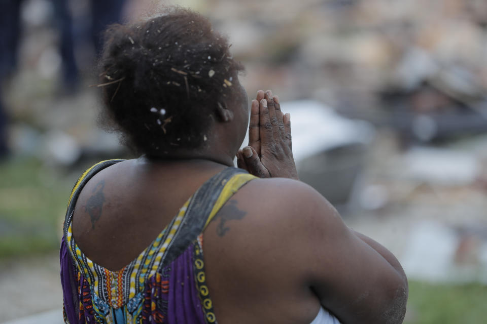 A woman stands in front of a pile of debris after an explosion in Baltimore on Monday, Aug. 10, 2020. Baltimore firefighters say an explosion has levelled several homes in the city. (AP Photo/Julio Cortez)