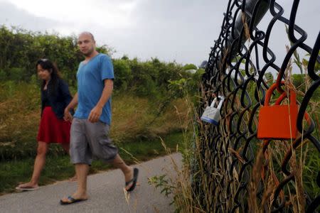 A couple walks past a lock left on a fence along the Cliff Walk in Newport, Rhode Island July 14, 2015. REUTERS/Brian Snyder